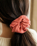 Close-up of the Salmon Shimmer kimono scrunchie worn on a low ponytail