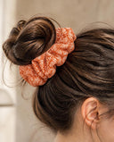 Close-up of the Orange Chrysanthemum kimono scrunchie worn on a messy bun