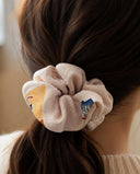 Close-up of the Sand Beige Blossom kimono scrunchie worn on a low ponytail