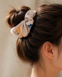 Close-up of the Sand Beige Blossom kimono scrunchie worn on a messy bun