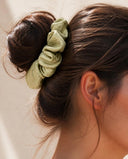 Close-up of the Sage Green kimono scrunchie worn on a messy bun